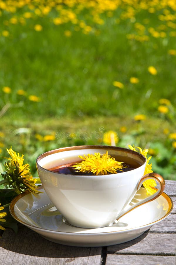 Dandelion tea in a white cup on a wooden table against a blurred