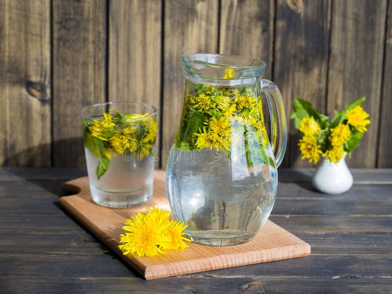 Dandelion tisane tea with fresh yellow blossom inside tea cup, on wooden table