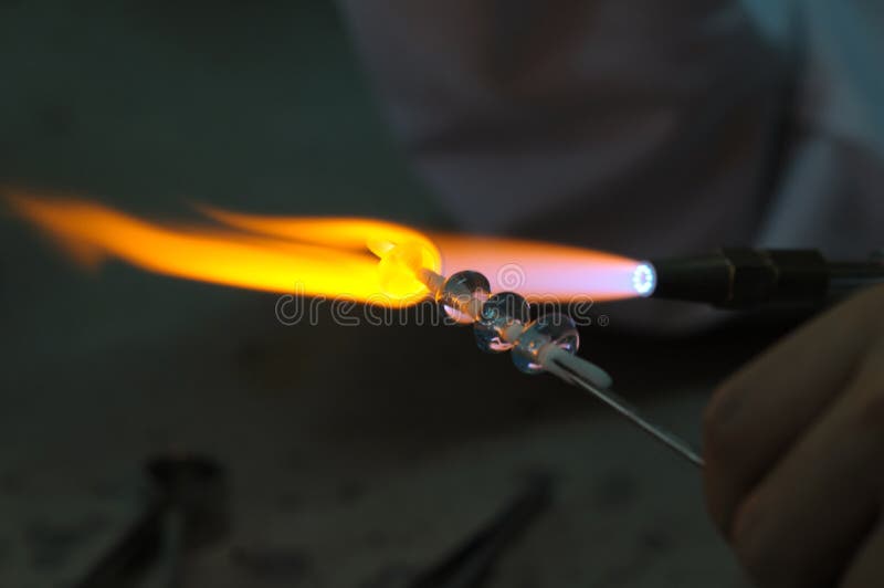 Artist shaping hot glass using a gas flame. Artist shaping hot glass using a gas flame