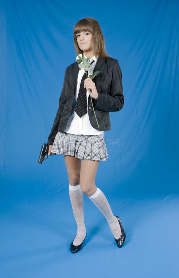 Beautiful young girl with pistol and flower in a hands on blue background. Beautiful young girl with pistol and flower in a hands on blue background