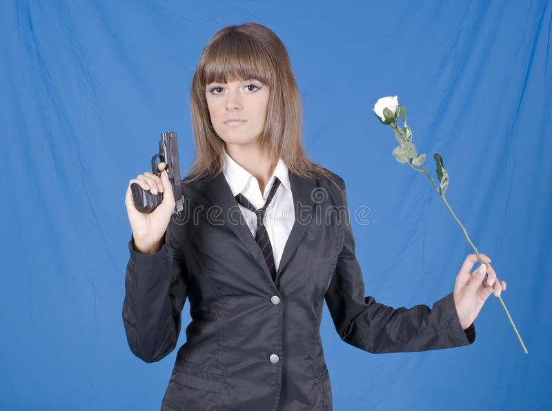 Beautiful young girl with pistol and flower in a hands on blue background. Beautiful young girl with pistol and flower in a hands on blue background