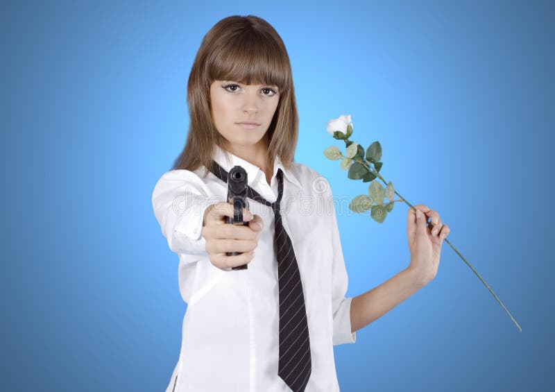 Beautiful young girl with pistol and flower in a hands on blue background. Beautiful young girl with pistol and flower in a hands on blue background