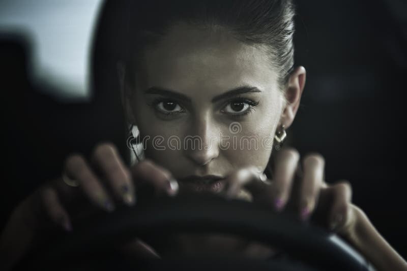 Dangerous beauty woman driving a car, close up portrait