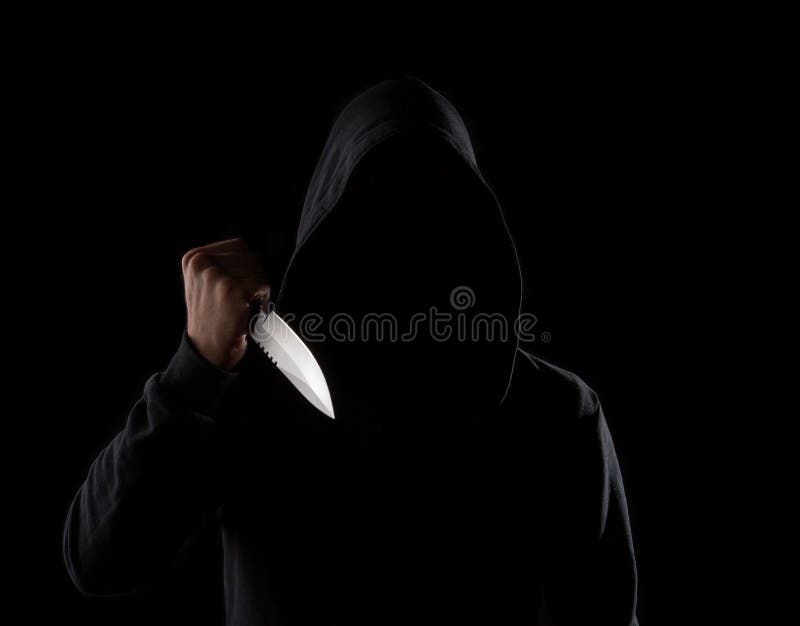 Dangerous hooded man holding knife. A dangerous hooded man standing in the dark and holding a shiny knife. Face can not be seen stock photography
