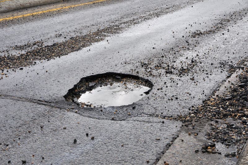 Pothole in the center of a busy city street. Pothole in the center of a busy city street.