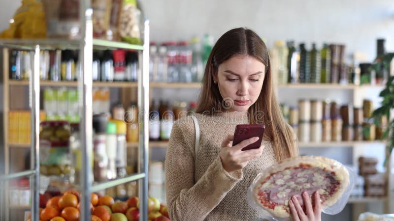 Dans le magasin fille scanne le code QR et prendre la lecture de pizza avec le remplissage prosciutto à l'aide de l'appareil photo clips vidéos
