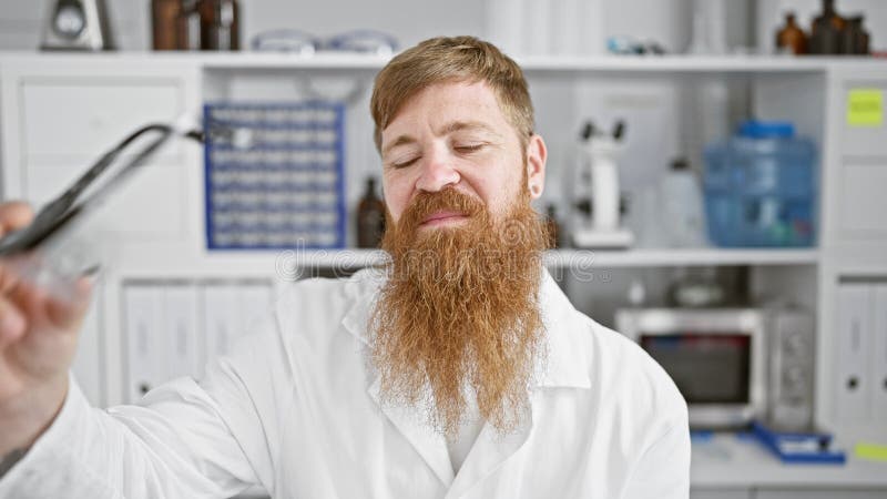 Dans un labo animé, un jeune rousse confiant qui clignote un sourire gagnant profite de l'excitation de la science beau scientifiq banque de vidéos