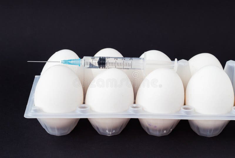 Dans un oeuf sur un fond noir, une seringue est injectée avec une hormone et des suppléments, un plan rapproché, les testicules e photos stock Dans un oeuf sur un fond noir, une seringue est injectée avec une hormone et des suppléments, un plan rapproché, les testicules e photos stock