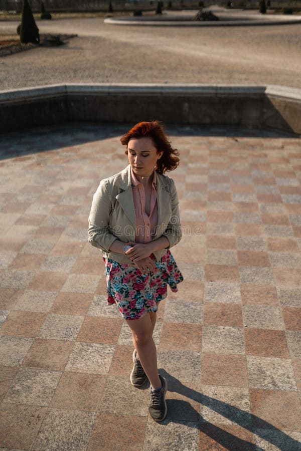 Danse heureuse de jeune femme dans une fontaine vide utilisant une jupe colorée photo stock Danse heureuse de jeune femme dans une fontaine vide utilisant une jupe colorée photo stock