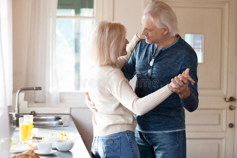 Danse supérieure romantique heureuse de couples dans la cuisine faisant cuire la nourriture image libre de droits Danse supérieure romantique heureuse de couples dans la cuisine faisant cuire la nourriture image libre de droits