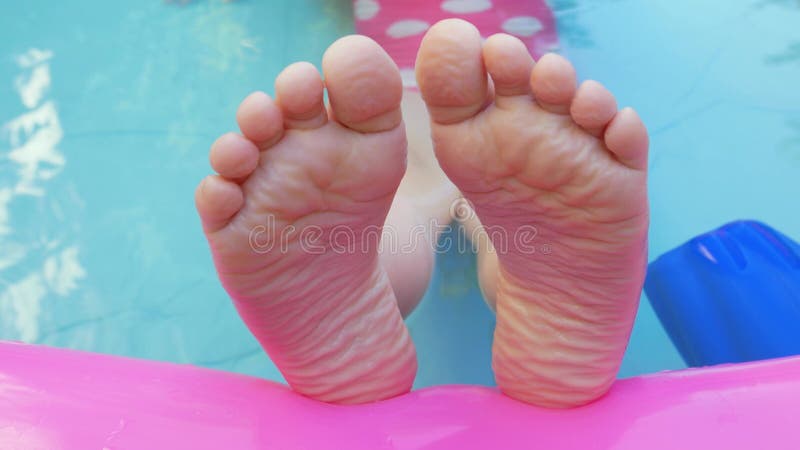 Danser pieds d'enfants dans la piscine gonflable coloré arc-en-ciel. Jeune fille en maillot de bain rose jouant dans l'eau 4k clips vidéos
