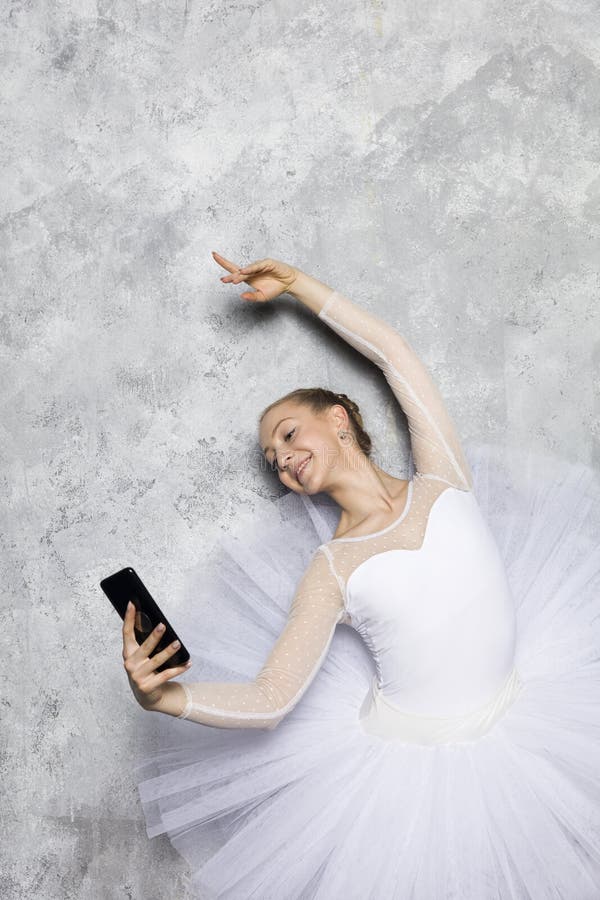Danseuse classique de jeune ballerine en tenant le téléphone de selfie contre le mur rustique photos libres de droits
