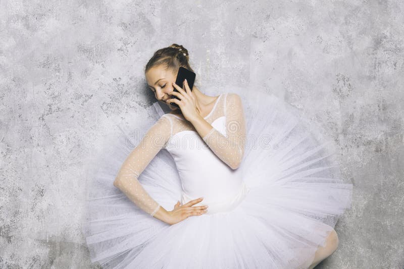 Danseuse classique de jeune ballerine en utilisant le téléphone portable contre le mur rustique images libres de droits