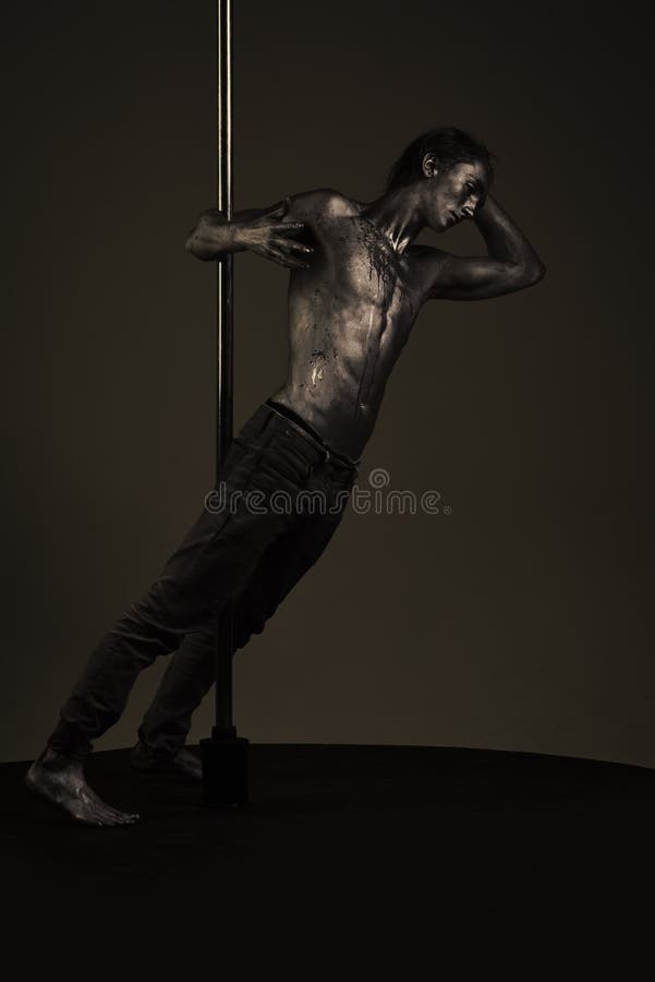 Danza de poste Hombre con el torso desnudo cubierto con la pintura brillante, fondo oscuro foto de archivo Danza de poste Hombre con el torso desnudo cubierto con la pintura brillante, fondo oscuro foto de archivo