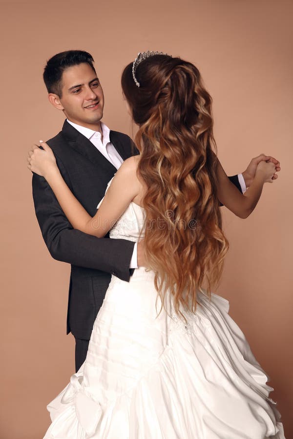 Dança dansing alegre do casamento do noivo e da noiva isolada no bege imagem de stock Dança dansing alegre do casamento do noivo e da noiva isolada no bege imagem de stock