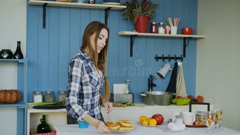 Dança engraçada nova alegre da mulher e canto ao cozinhar o café da manhã em casa