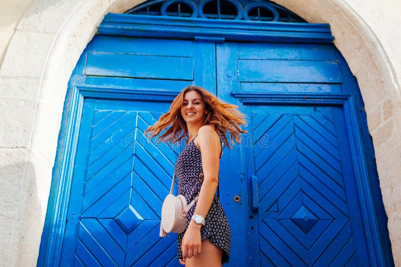 Dança feliz da jovem mulher contra a porta de madeira azul Retrato exterior da menina adolescente bonita que tem o divertimento fotos de stock royalty free Dança feliz da jovem mulher contra a porta de madeira azul Retrato exterior da menina adolescente bonita que tem o divertimento fotos de stock royalty free
