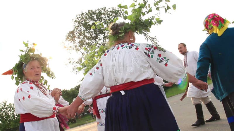 A dança redonda étnica, jovens idosos recolheu o canto de passeio