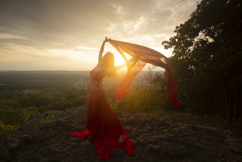 Female dancer in red dress, waving into the wind at sunset on the mountain a red fabric with Chinese calligraphy on it, at Penwood State Park in Bloomfield, Connecticut. Female dancer in red dress, waving into the wind at sunset on the mountain a red fabric with Chinese calligraphy on it, at Penwood State Park in Bloomfield, Connecticut