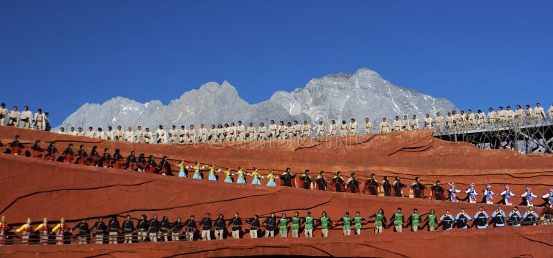 Dancers dressed in ethnic costumes at Impression Lijiang against background of Jade Dragon Snow Mountain, Lijiang, Yunnan, China. Dancers dressed in ethnic costumes at Impression Lijiang against background of Jade Dragon Snow Mountain, Lijiang, Yunnan, China