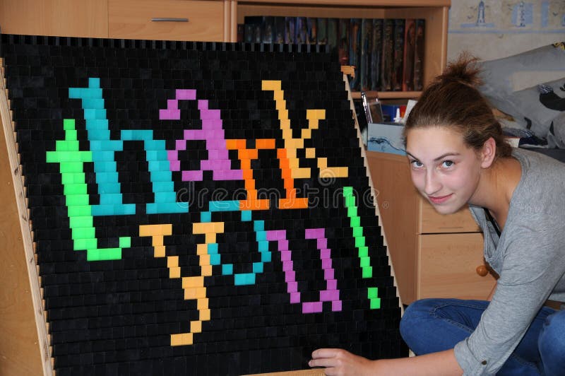 Teenager girl builds the words thank you at the fall wall with domino blocs. Teenager girl builds the words thank you at the fall wall with domino blocs