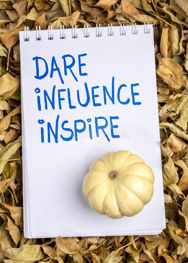 Dare, influence, inspire - handwriting in a spiral art sketchbook with ornamental gourd against dry fall leaves. Dare, influence, inspire - handwriting in a spiral art sketchbook with ornamental gourd against dry fall leaves