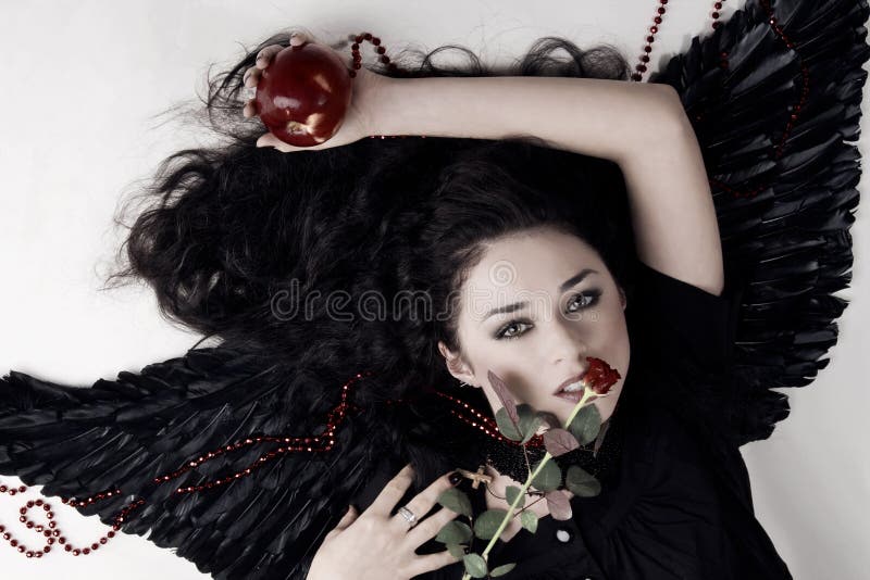 Dark angel girl with a red apple and rose