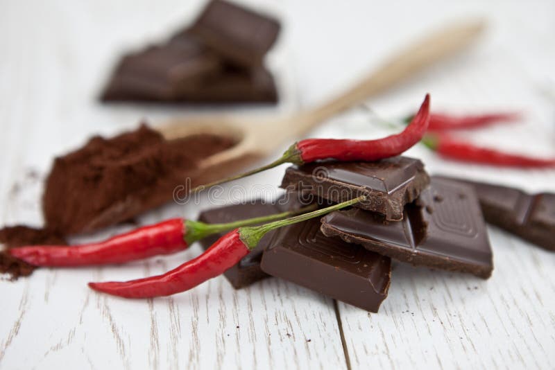 Pieces Of Chocolate With Chili Peppers On A Wooden Table Stock Photo