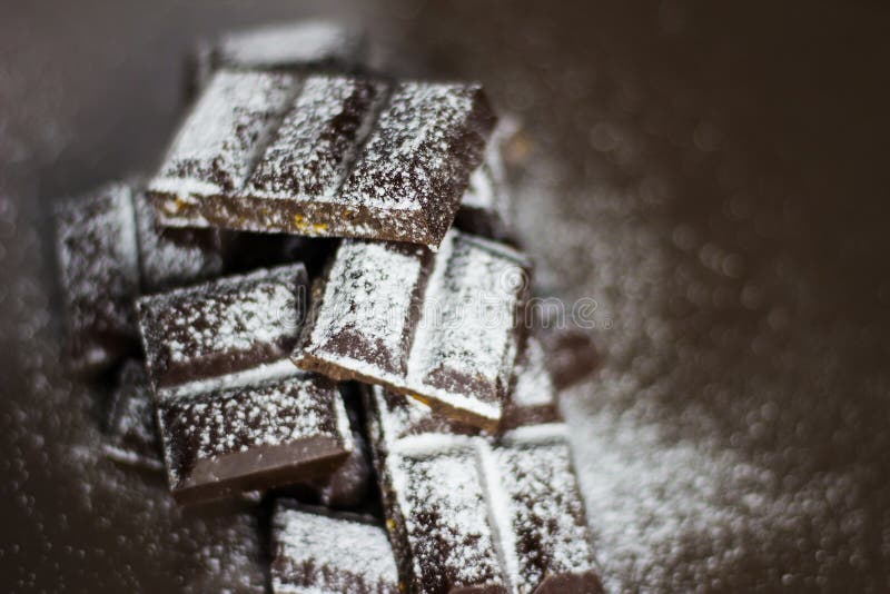 Dark Chocolate in Powdered Sugar. Chunks of Dark Chocolate Stock Photo