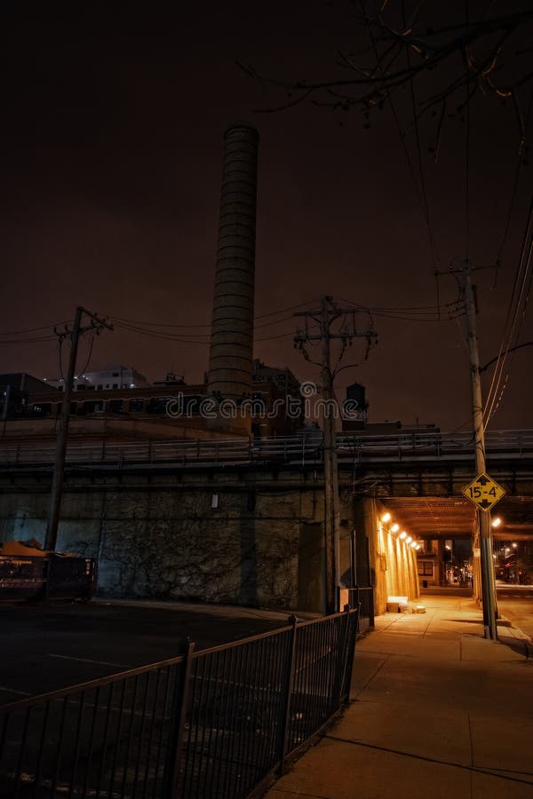 Dark urban downtown city elevated train underpass with smokestack and sidewalk at night. Night train stock images, royalty-free photos and pictures