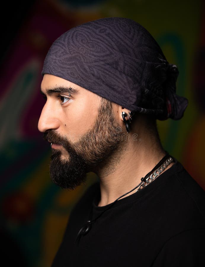 Dark studio portrait of a young man with piercing.