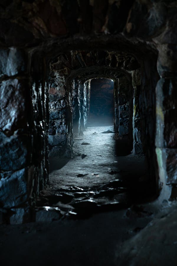 A dark, damp, creepy and cold dungeon corridor with stone walls all along the hallway