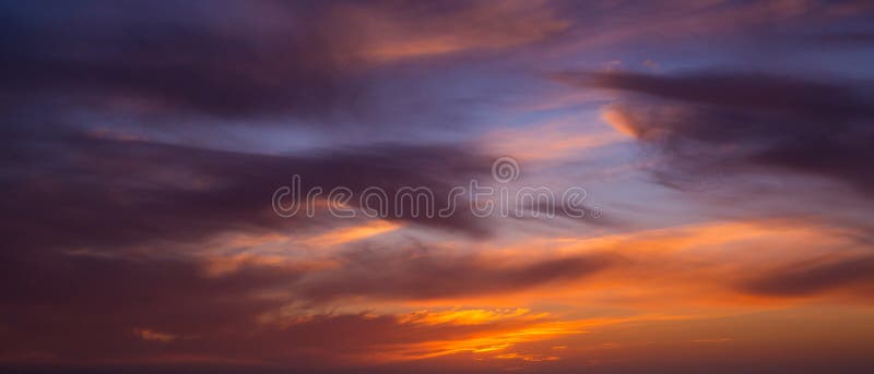 Dark dramatic clouds in sky at sunset with blue orange gradient stock photography