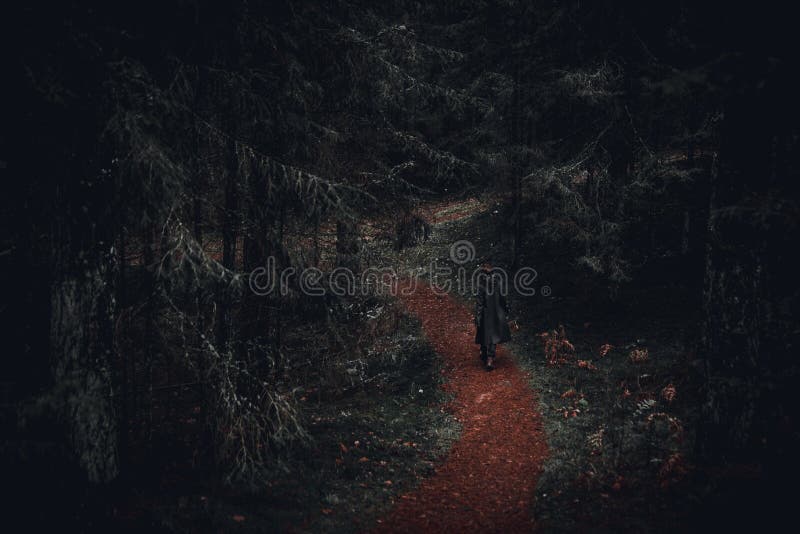 Dark dressed girl walking on the path of dark forest
