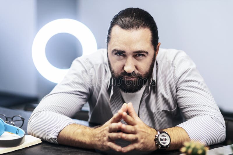 Dark-haired bearded man with a big watch on his hand looking focused