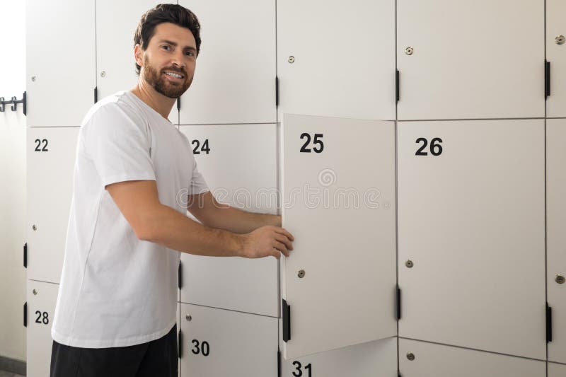 Dark-haired bearded man in changing room in gym royalty free stock image
