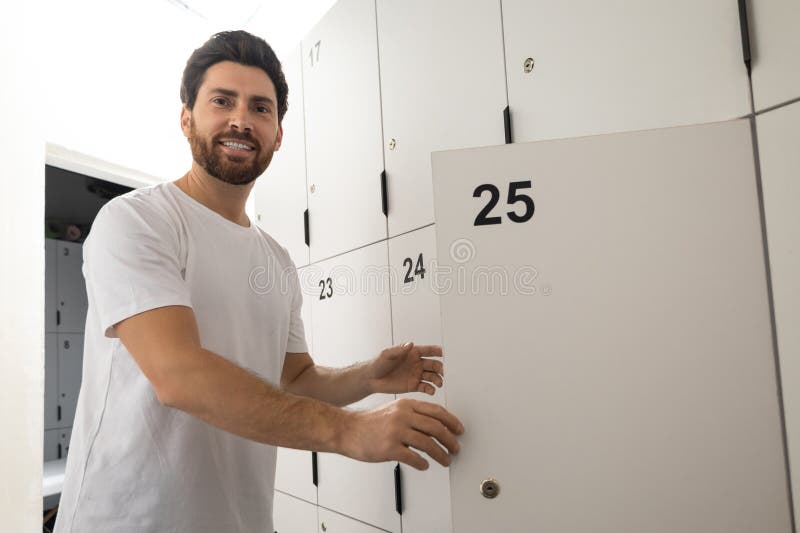 Dark-haired bearded man in changing room in gym royalty free stock photo