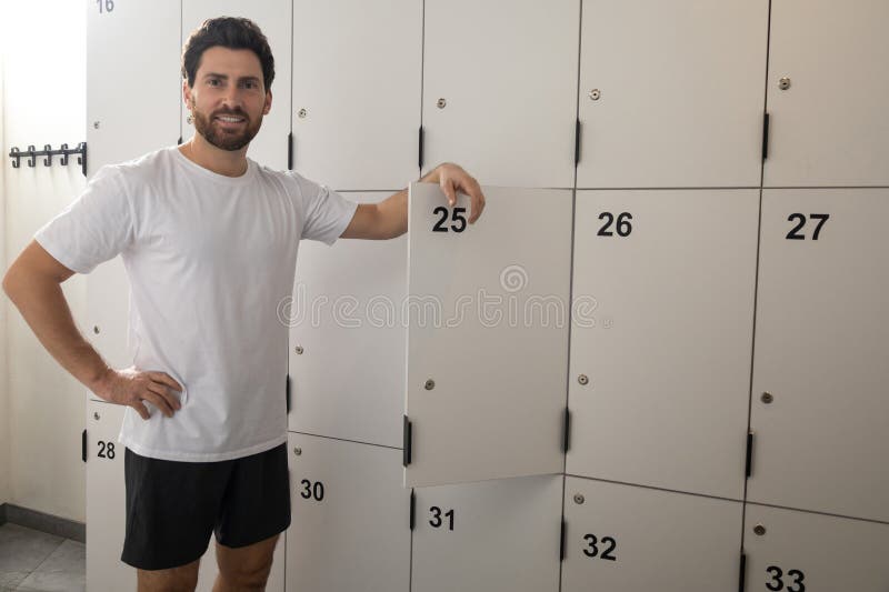 Dark-haired bearded man in changing room in gym royalty free stock images