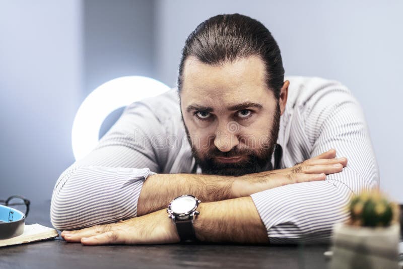 Dark-haired bearded man in a striped shirt feeling tired royalty free stock photo