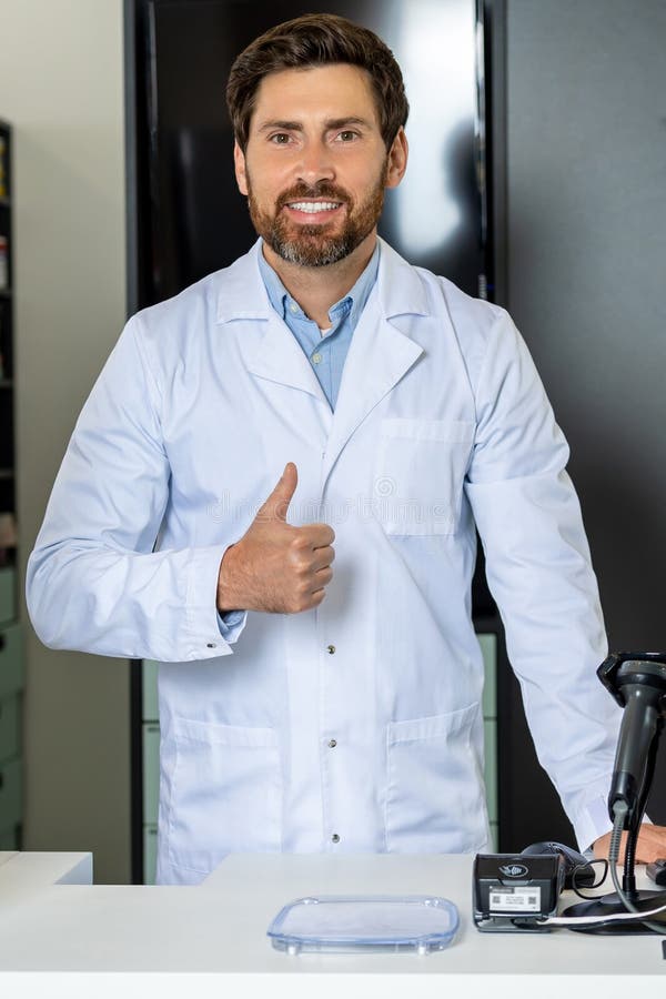 Dark-haired bearded pharmacist in a lab coat looking confident and contented royalty free stock photo
