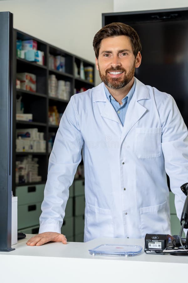 Dark-haired bearded pharmacist in a lab coat looking confident and contented royalty free stock image