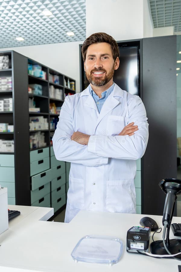 Dark-haired bearded pharmacist in a lab coat looking confident and contented royalty free stock images