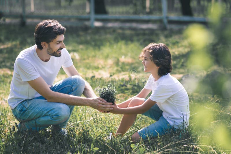 Dark-haired boy and his father holding the plant and smiling royalty free stock photography