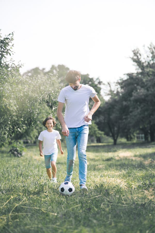 Dark-haired boy and his father playing with the ball in the garden stock photos