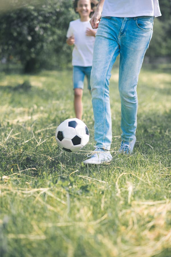 Dark-haired boy and his father running with the ball stock images