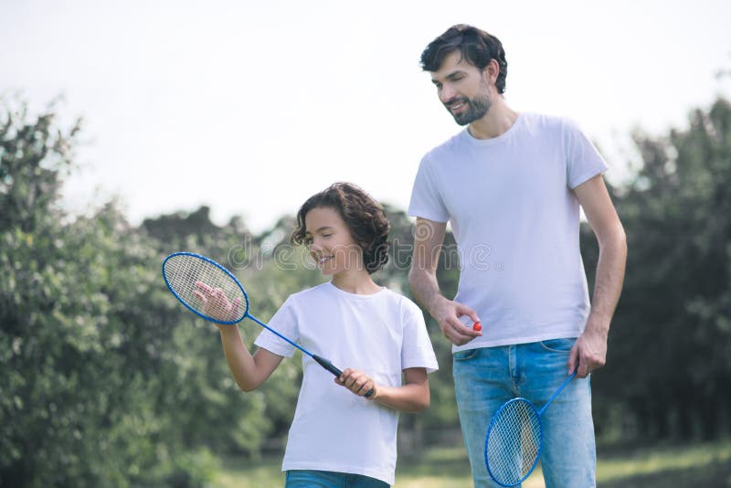 Dark-haired boy holding badminton racket ready to play with his dad royalty free stock photo