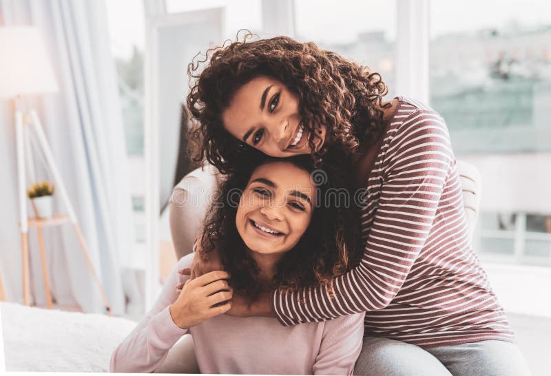 Dark-haired girl feeling loved while hugging her caring sister royalty free stock images Dark-haired girl feeling loved while hugging her caring sister royalty free stock images