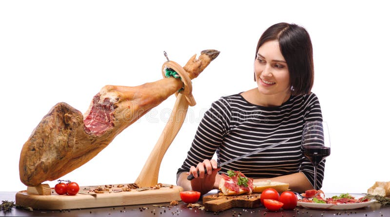 The dark-haired girl looks at a whole jamon on a wooden stand. Isolated over white background