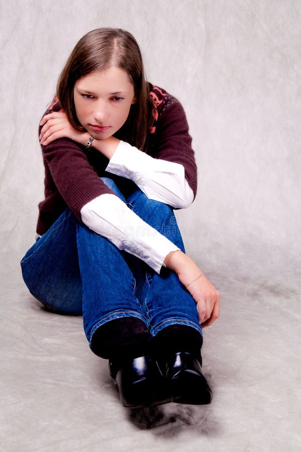 Dark haired girl sitting thinking on white