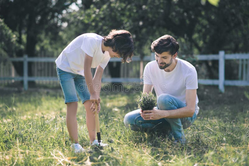 Dark-haired man holding the plant and talking, his son listening to him royalty free stock photo